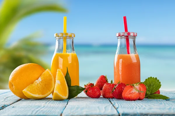 Sumo fresco com mistura de frutas na praia — Fotografia de Stock