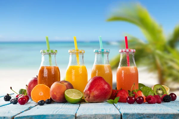 Sumo fresco com mistura de frutas na praia — Fotografia de Stock