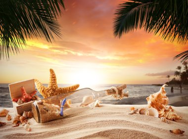 Şişe ve deniz yıldızı olan Sandy tropikal plaj