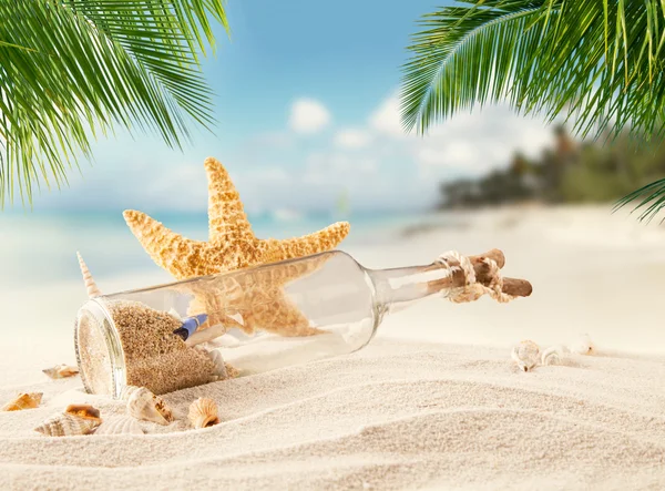Sandy tropical beach with bottle and starfish — Stock Photo, Image