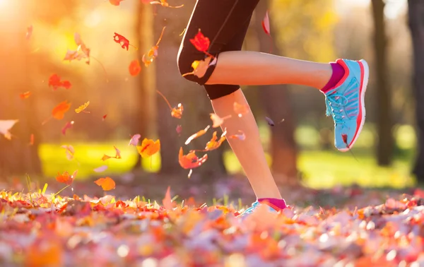 Primer plano de los pies de un corredor corriendo en hojas — Foto de Stock