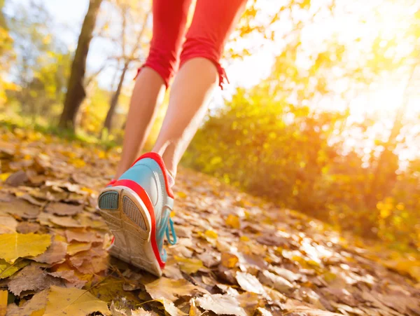 Primer plano de los pies de un corredor corriendo en hojas — Foto de Stock