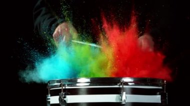 Bateristin renkli barut patlamasıyla davullara vuruşunun süper yavaş çekimi. Yüksek hızlı sinema kamerası, 1000 fps..