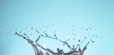 Abstract crown shape of water splash on blue background, studio shot