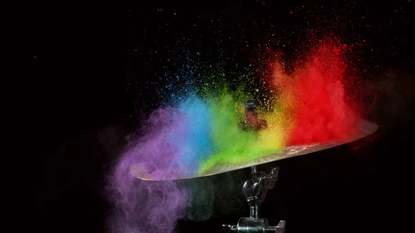 Freeze motion of coloured powder explosion on drum cymbal isolated on black background