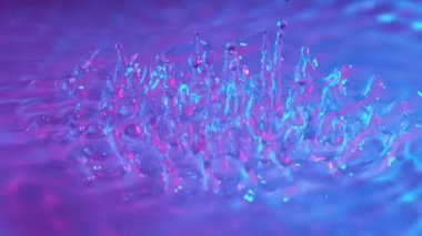 Neon ışıklarıyla aydınlatılmış su sıçratmanın süper yavaş çekimi. Çok hızlı bir kamerayla çekildi, 1000 fps..