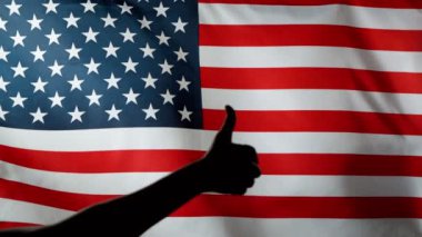 ABD bayrağını baş parmağında siluetle sallamak çok yavaş bir hareket. Zafer jesti. Yüksek hızlı sinema kamerası, 1000fps.