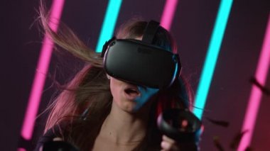 VR gözlüklü genç kadın yavaş hareket ediyor, neon ışıklı sanal gerçeklik. Yüksek hızlı sinema kamerasıyla çekilmiş..