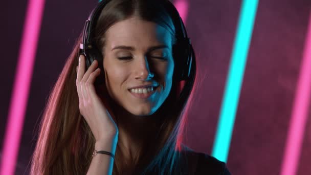 ネオンを背景に音楽を聴く若い女性のスローモーション 高速シネマカメラで撮影 — ストック動画