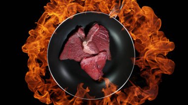 Biftek tavada, alevler arka planda. Yüksek açılı et hazırlama, stüdyo çekimi.