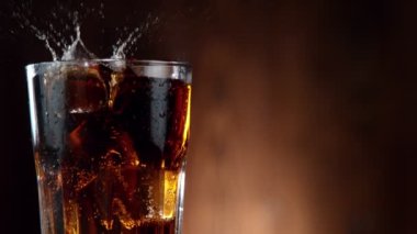 Buz küpünün kola içeceğine düşmesi çok yavaş bir hareket, kamera hareketi. Yüksek hızlı sinema kamerası, 1000 fps.