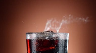 Buz küpünün kola içeceğine düşmesi çok yavaş bir hareket, kamera hareketi. Yüksek hızlı sinema kamerası, 1000 fps.