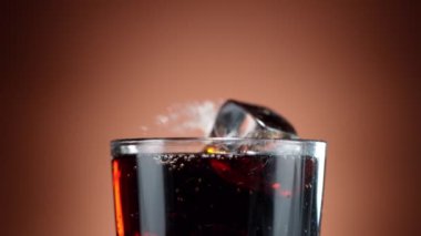 Buz küpünün kola içeceğine düşmesi çok yavaş bir hareket, kamera hareketi. Yüksek hızlı sinema kamerası, 1000 fps.