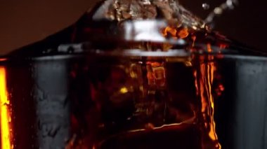 Buz küpünün kola içeceğine düşmesi çok yavaş bir hareket, kamera hareketi. Yüksek hızlı sinema kamerası, 1000 fps.