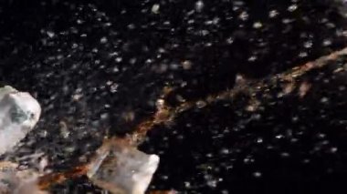 Siyah arka planda buz küpleri olan çok yavaş bir kola sıçraması. Yüksek hızlı sinema kamerası, 1000 fps.