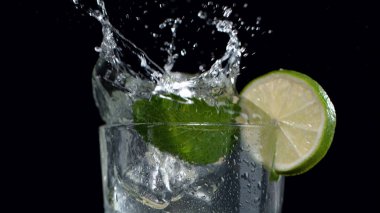 Mojito su sıçratarak içer, yakın plan, siyah arka plan izole edilir.