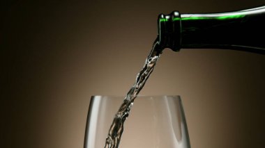 Siyah arka planda şarap kadehine beyaz şarap dökmek, stüdyo çekimi.