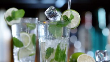 Mojito içeceğine düşen buz küpünün süper yavaş çekimi, kamera hareketi. Yüksek hızlı sinema kamerası, 1000 fps..