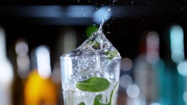 Mojito içeceğine düşen buz küpünün süper yavaş çekimi, kamera hareketi. Yüksek hızlı sinema kamerası, 1000 fps..