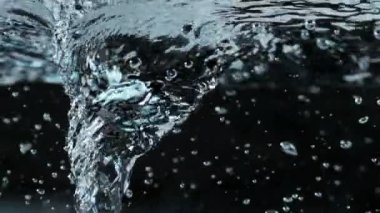 Kasırga şeklinde, karanlık arka planda akan suyun süper yavaş çekimi. Yüksek hızlı sinema kamerası, 1000 fps..