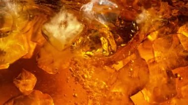 Kola ya da alkollü içecek içinde dönen buz küplerinin süper yavaş çekimleri. Yüksek hızlı sinema kamerası, 1000 fps..
