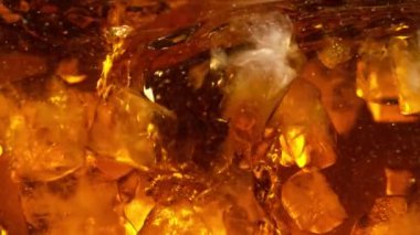 Kola ya da alkollü içecek içinde dönen buz küplerinin süper yavaş çekimleri. Yüksek hızlı sinema kamerası, 1000 fps..