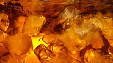 Kola ya da alkollü içecek içinde dönen buz küplerinin süper yavaş çekimleri. Yüksek hızlı sinema kamerası, 1000 fps..