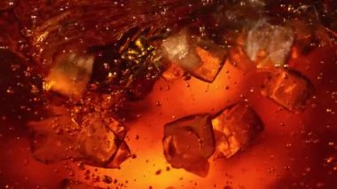 Kola ya da alkollü içecek içinde dönen buz küplerinin süper yavaş çekimleri. Yüksek hızlı sinema kamerası, 1000 fps..