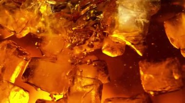 Kola ya da alkollü içecek içinde dönen buz küplerinin süper yavaş çekimleri. Yüksek hızlı sinema kamerası, 1000 fps..