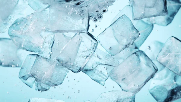 Detail of whirling water with ice cubes, closeup. Abstract aqua background.