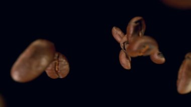 Siyah arka planda izole kahve çekirdekleri çok yavaş düşüyor. Yüksek hızlı sinema kamerası, 1000fps.