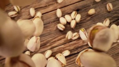 Ahşap arka planda düşen şam fıstığının süper yavaş çekimi. Yüksek hızlı sinema kamerası, 1000fps.