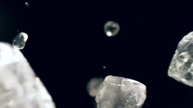 Limon dilimlerinin süper yavaş çekimde siyah arka planda buz kalıplarıyla düşüşü. Yüksek hızlı sinema kamerası, 1000 fps..