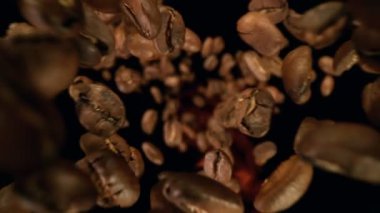 Siyah arka planda izole edilmiş ateş tanecikli kahve çekirdekleri süper yavaş çekimde. Yüksek hızlı sinema kamerası, 1000fps.