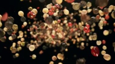 Siyah arka planda düşen renkli biber baharatının süper yavaş çekimi. Yüksek hızlı kamera, 1000 fps.