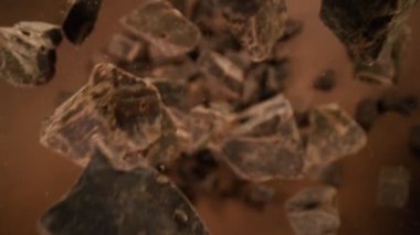 Düşen bir grup çiğ çikolata parçasının süper yavaş çekimi. Yüksek hızlı sinema kamerası, 1000fps.