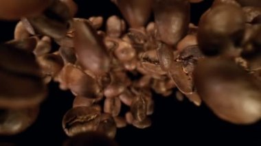 Siyah arka planda izole kahve çekirdekleri çok yavaş düşüyor. Yüksek hızlı sinema kamerası, 1000fps.