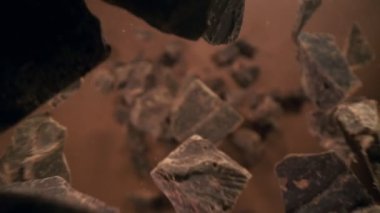 Düşen bir grup çiğ çikolata parçasının süper yavaş çekimi. Yüksek hızlı sinema kamerası, 1000fps.