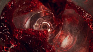 Kırmızı şarap bir bardağa dökülüyor, yakın plan, soyut arka plan