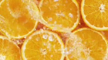Su sıçratan portakal dilimlerinin süper yavaş çekimi, üst manzara. Yüksek hızlı sinema kamerası, 1000 fps..
