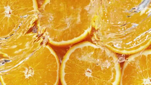Super Langzame Beweging Van Sinaasappelschijfjes Met Spetterend Water Bovenaanzicht Gefilmd — Stockvideo
