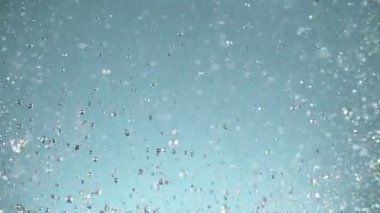 Mavi arka planda izole edilmiş çok yavaş su sıçratma hareketi. Yüksek hızlı sinema kamerası, 1000 fps..