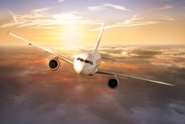 Günbatımında bulutların üzerinde uçan ticari uçaklar. Hızlı seyahat, tatil ve iş kavramı.