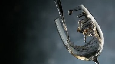 Süper yavaş çekimde beyaz şarap bardağa doluyor. Detaylı olarak, hız rampası etkisi. Yüksek hızlı sinema kamerası, 1000 fps.