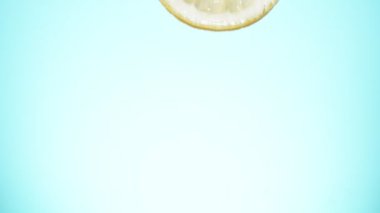 Limon, portakal ve limon dilimleri suya çok yavaş düşüyor. Hız rampası etkisi. Yüksek hızlı sinema kamerası, 1000 fps..