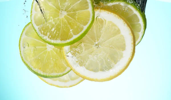Verse Limoenen Citroenen Schijfjes Water Gedropt Met Plons Studio Shot — Stockfoto