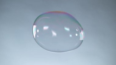Gri arka planda büyük bir baloncukla uçmanın süper yavaş çekimi. Yüksek hızlı sinema kamerası, 1000fps.