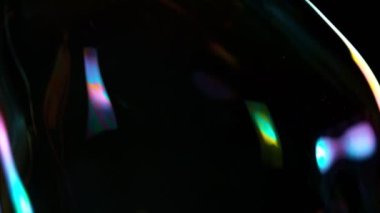 Siyah arka planda büyük bir baloncukla uçmanın süper yavaş çekimi, yakın plan. Yüksek hızlı sinema kamerası, 1000fps.