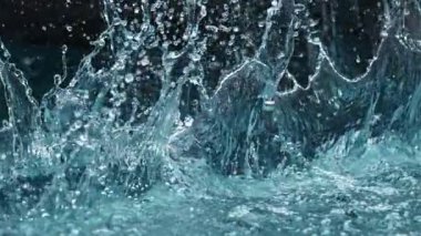 Mavi arka planda izole edilmiş çok yavaş su sıçratma hareketi. Yüksek hızlı sinema kamerası, 1000 fps..