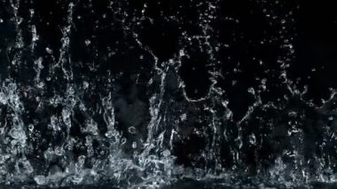 Mavi arka planda izole edilmiş çok yavaş su sıçratma hareketi. Yüksek hızlı sinema kamerası, 1000 fps..